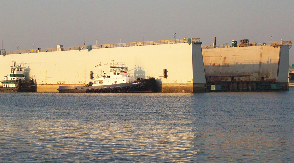 Tugs_move_dockside_drydock_toward_end_of_construction_hall